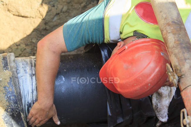 Travailleur de la construction guidant la conduite d'eau — Photo de stock