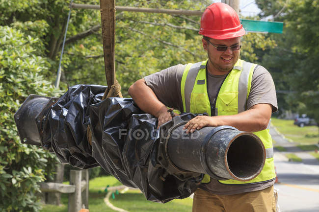 Trabalhador da construção civil que guia a conduta da água — Fotografia de Stock