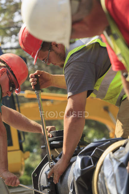 Travailleurs de la construction utilisant une clé dynamométrique pour sécuriser la section principale de l'eau avec des boulons — Photo de stock