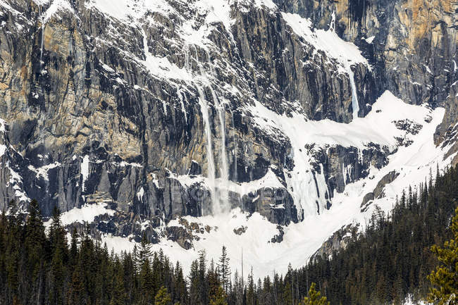 Scenic of mountain cliff face with avalanche snow cascading over cliffs; Field, British Columbia, Canada — Stock Photo