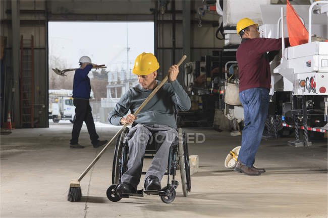 Maintenance technicians, one with a spinal cord injury, cleaning in utility truck garage at electric power plant — Stock Photo