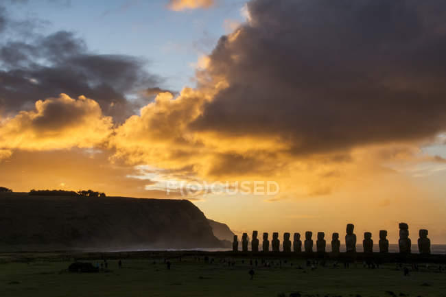 Los quince moais de Tongariki se silueta contra el cielo brillantemente coloreado de la salida del sol; Isla de Pascua, Chile - foto de stock