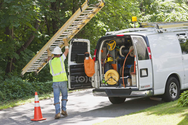 Lineman carregando uma escada de volta para seu caminhão — Fotografia de Stock