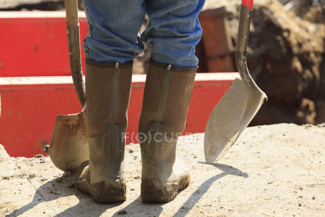 Construction worker preparing to enter shored up hole with shovels — Stock Photo