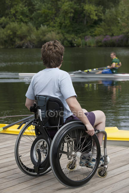 Mulher com lesão medular sentada em uma cadeira de rodas no cais — Fotografia de Stock