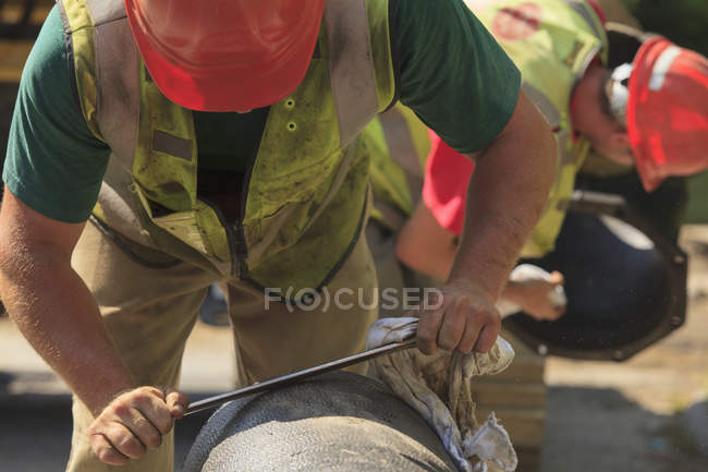 Construction worker smoothing rough edge of water main — Stock Photo
