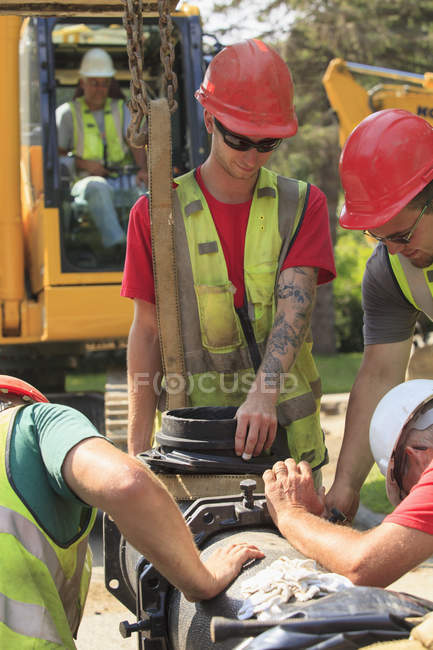 Trabalhadores da construção que unem secções da rede de distribuição de água — Fotografia de Stock
