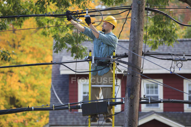Lineman working on cables at power pole — Stock Photo