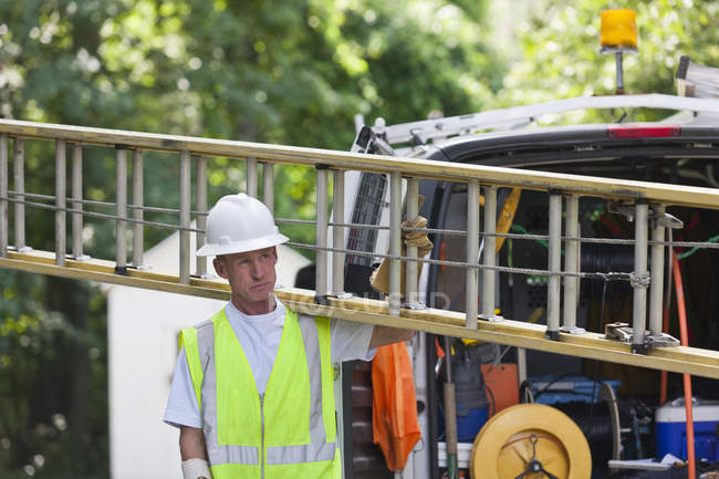 Trabalhador de comunicações carregando uma escada do caminhão para fazer a instalação — Fotografia de Stock