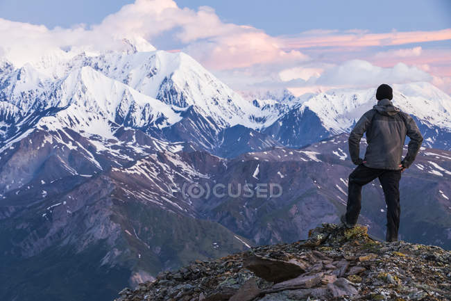 Vista trasera del hombre en la parte superior de las montañas cubiertas de nieve en Alaska Range; Alaska, Estados Unidos de América - foto de stock