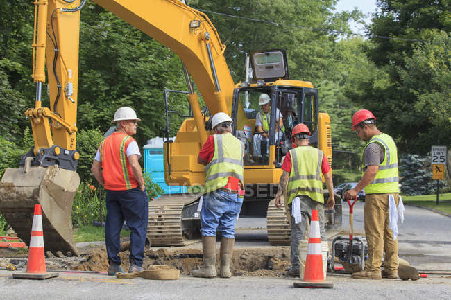 Construction workers digging hole to replace watermain — Stock Photo