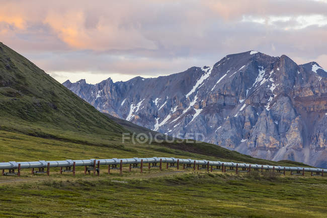 The Trans-Alaska Pipeline stretches across the tundra beneath the craggy mountains of the Brooks Range; Alaska, United States of America — Stock Photo