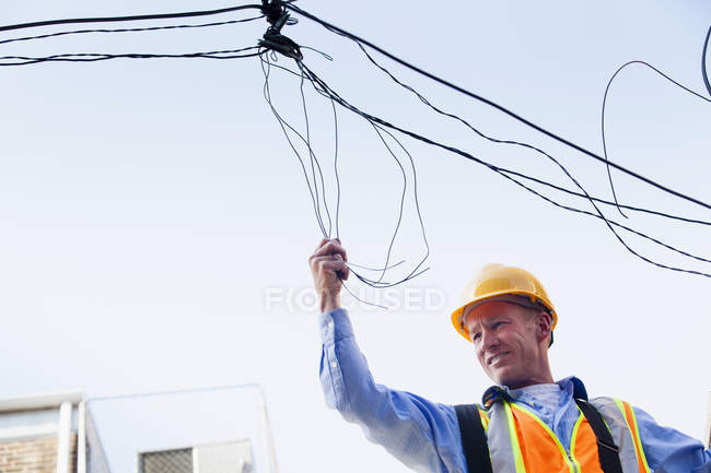 Cable lineman on ladder fixing dangling wires — Stock Photo