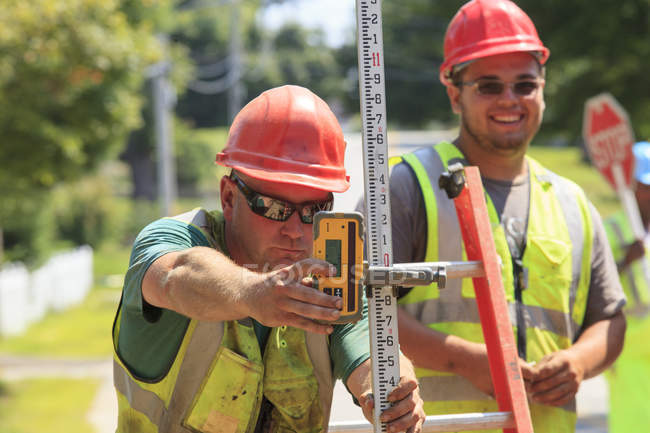 Construction supervisor using electronic surveying rod — Stock Photo