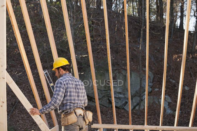 Carpenter preparing to use level on house framing — Stock Photo