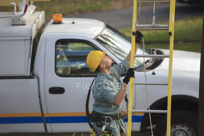 Lineman placing ladder at power pole — Stock Photo