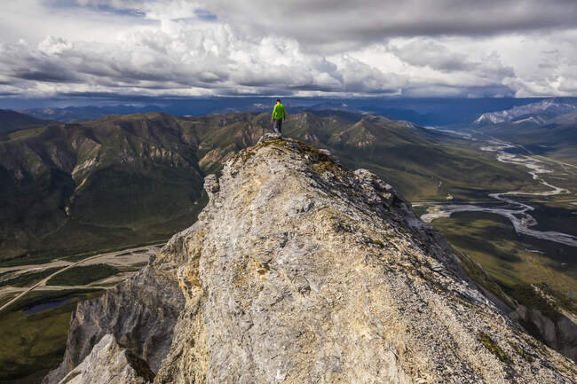 A hiker treading carefully above cliffs near the summit of Sukakpak Mountain in the Brooks Range; Alaska, United States of America — Stock Photo