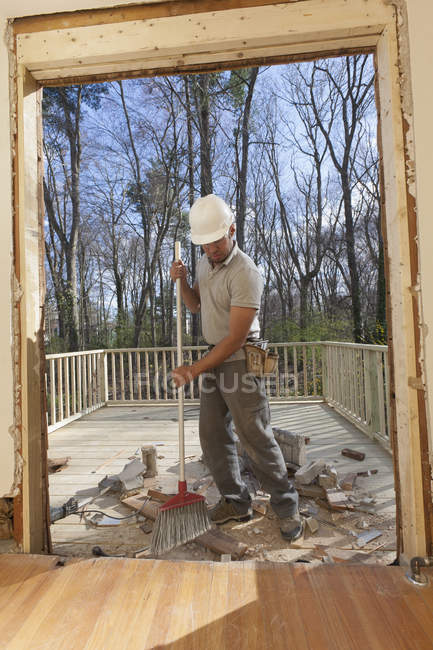 Латиноамериканский плотник чистит недавно вырезанный вход из дома в палубу — стоковое фото
