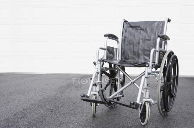 Sedia a rotelle vuota davanti a un garage — Foto stock