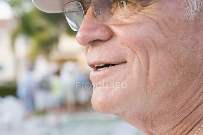 Primer plano de un hombre mayor sonriendo y mirando hacia otro lado - foto de stock