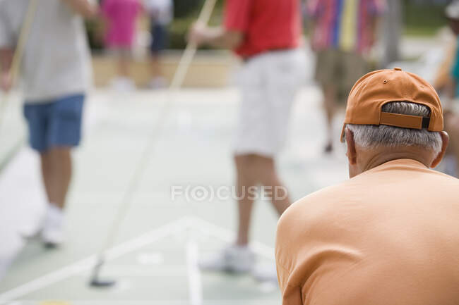 Vista trasera de un hombre mayor jugando al shuffleboard - foto de stock