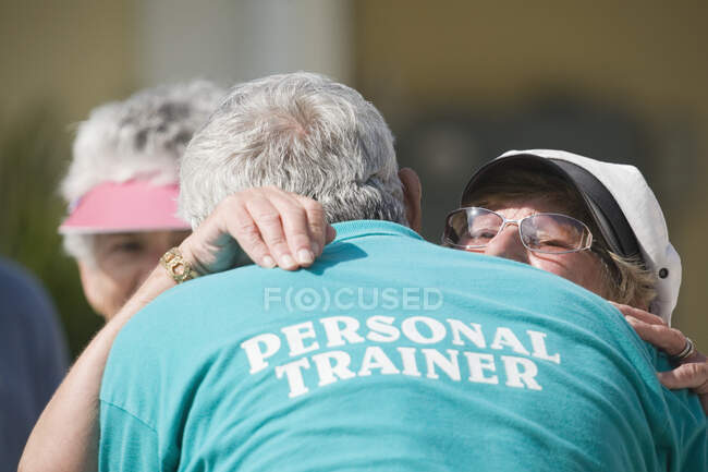 Senior woman hugging with her trainer — Stock Photo