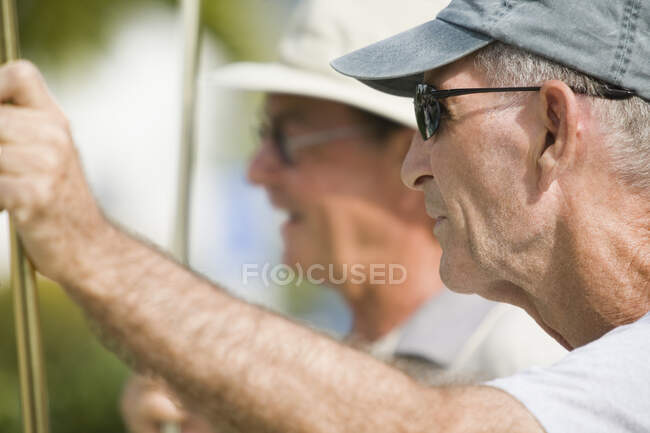 Побочный профиль пожилого человека, держащего шаффлборд-кий — стоковое фото
