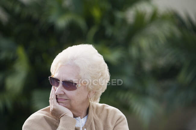 Primer plano de una mujer mayor con la mano en la barbilla - foto de stock