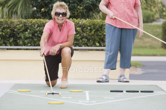 Две пожилые женщины играют в шаффлборд — стоковое фото