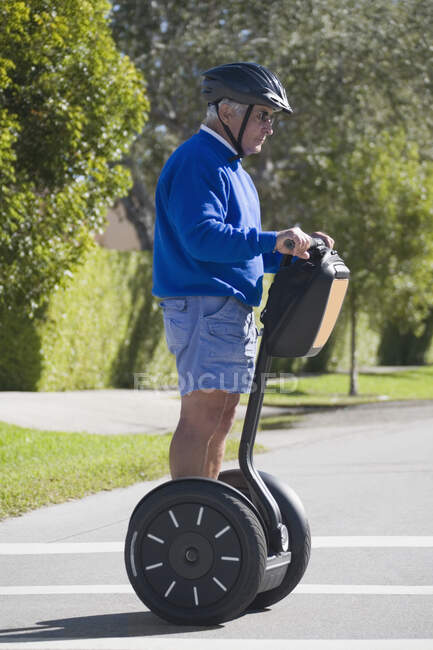Perfil lateral de un hombre mayor montando un segway - foto de stock