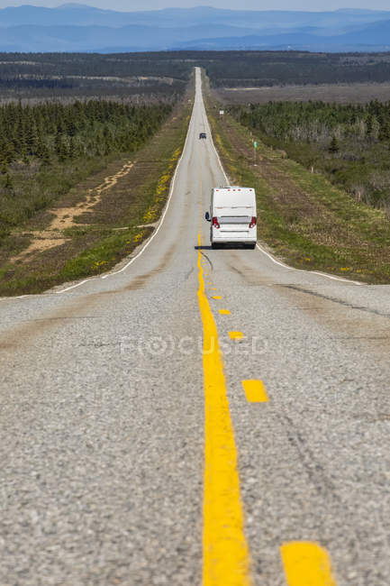 Туристический автобус едет по длинному, одинокому участку шоссе между Дельта Джанкшен и Паксон, Аляска. Milepost 248, Old Richarson Highway; Аляска, США — стоковое фото