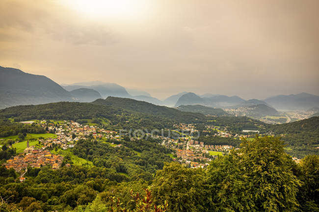 Sunlight glowing through the overcast sky over the rolling hills of Lugano; Lugano, Ticino, Switzerland — Stock Photo