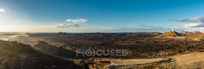 Обширный исландский пейзаж и Рейкьявисский маяк вдали, старейший маяк в Исландии, на холме Баярфелл, Рейкьявисский полуостров; Исландия — стоковое фото