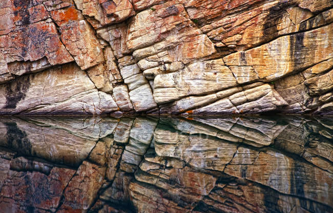 Rock wall surface reflected in tranquil water of Horseshoe Lake, Jasper National Park; Alberta, Canada — стокове фото