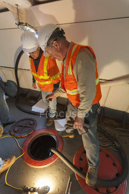 Environmental cleanup engineers in hold of ship cleaning hazardous materials — Stock Photo