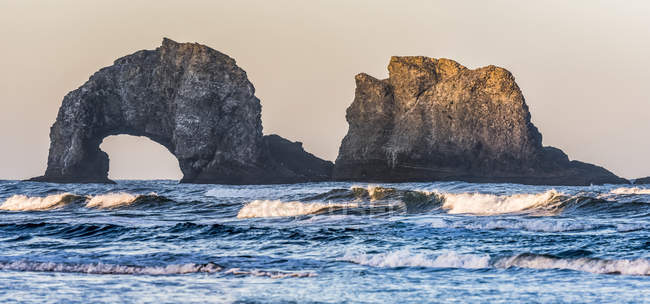 Twin Rocks sono illuminati dal sole nascente vicino Rockaway; Oregon, Stati Uniti d'America — Foto stock