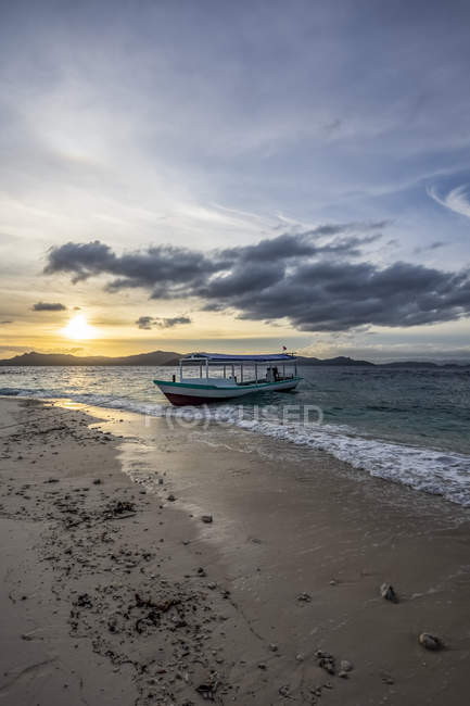 Bateau sur la plage au coucher du soleil, Pulau Kelelawar (île de Bat) ; Papouasie occidentale, Indonésie — Photo de stock