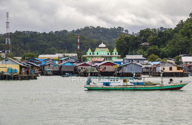 Puerto de Sorong con edificios coloridos y un barco; Sorong, Papúa Occidental, Indonesia - foto de stock
