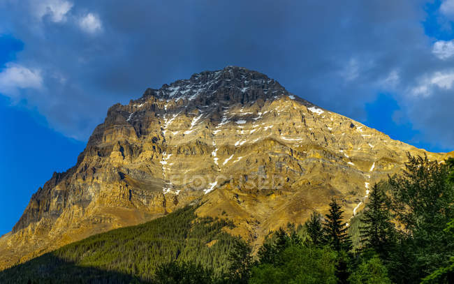Rugged mountain in the Canadian Rocky mountains illuminated by sunlight with a shaded peak, Yoho National Park; Field, British Columbia, Canada — Stock Photo
