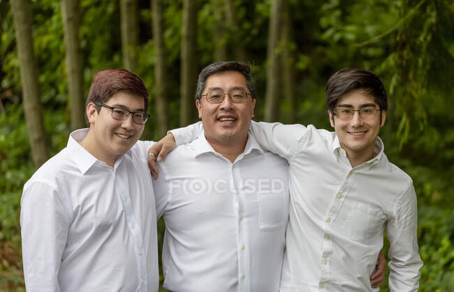 Um retrato de um pai com dois filhos, todos vestindo camisas brancas; Langley, British Columbia, Canadá — Fotografia de Stock