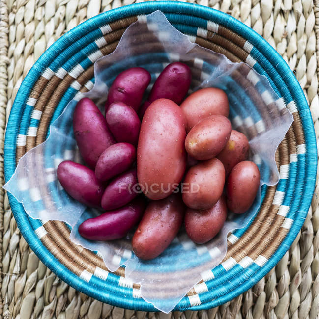 Woven basket full of fresh potatoes; Studio — Stock Photo