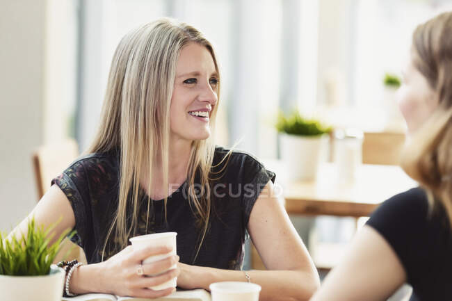 Une chrétienne mûre encadrant et faisant une étude biblique avec une jeune femme dans un café : Edmonton, Alberta, Canada — Photo de stock
