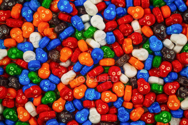 Colorato mucchio di caramelle cranio in rosso, blu, arancione, verde, bianco, arancione e marrone — Foto stock