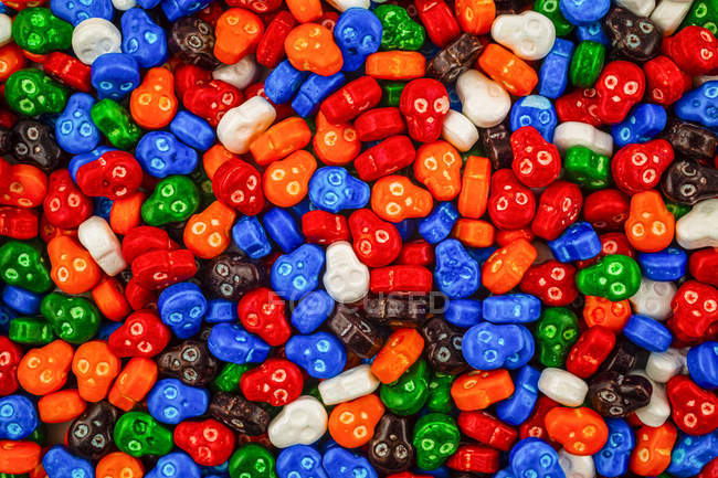 Pile colorée de bonbons crâne en rouge, bleu, orange, vert, blanc, orange et brun — Photo de stock