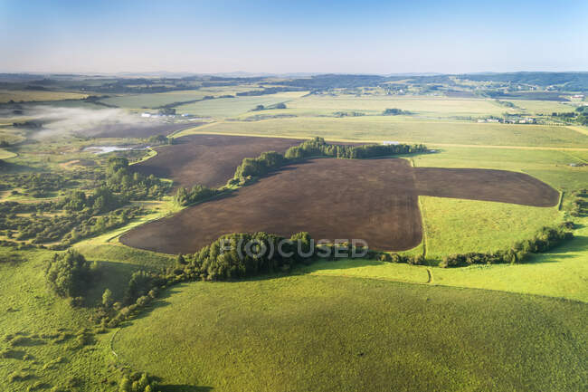 Aerial view of a dark clean soil field surrounded by trees and green fields, West of Calgary; Alberta, Canada — Stock Photo