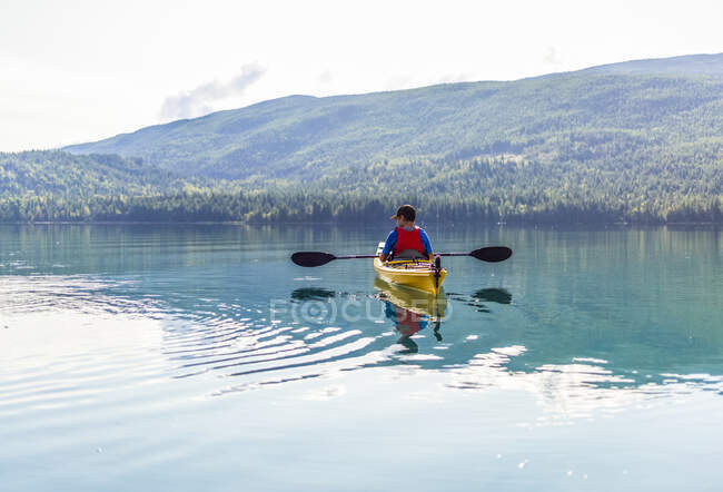 Adolescente haciendo kayak en White Lake, White Lake Provincial Park; Columbia Británica, Canadá - foto de stock