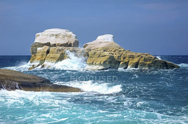 L'acqua blu del Mediterraneo si getta contro formazioni rocciose bianche lungo la costa di un'isola greca; Milos, Grecia — Foto stock