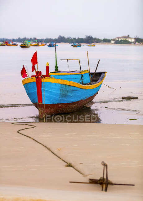 Colorido barco de pesca atado a la playa, Ke Ga Cape; Ke Ga, Vietnam - foto de stock