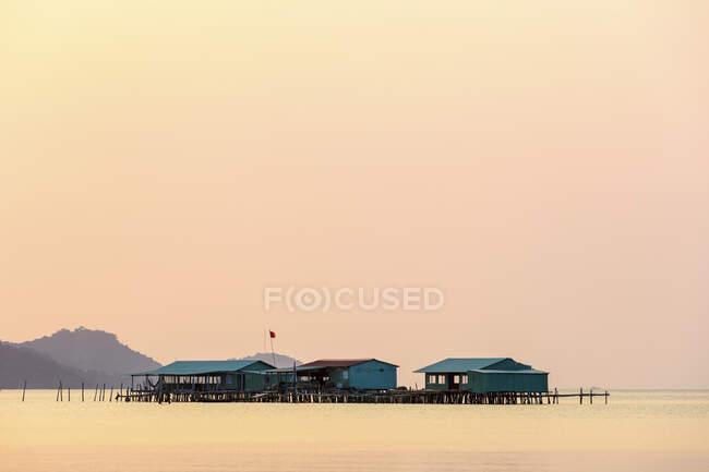 Підняті будинки на воді під час яскравого рожевого заходу на заході сонця, пляж Старфіш; Фукуок, провінція Кьєн - Джанг, В 