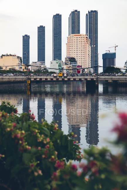 Skyscrapers in a row form the skyline and reflect in the water of the Saigon River; Ho Chi Minh City, Vietnam — Stock Photo